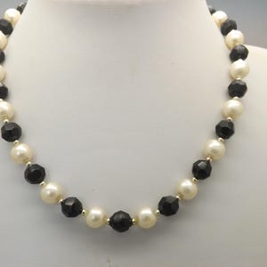 A very fine handmade single strand vintage jewelry necklace made with polished black and cream faux pearls with silvertone spacer beads
