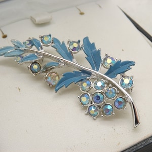 A superb early flower and leaf spray design vintage jewelry brooch in silvertone metal and blue enamel with sparkly aurora borealis stones
