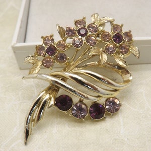 A superb flower spray goldtone vintage costume jewelry brooch set with sparkly deep rich amethyst and pink faceted round glass stones