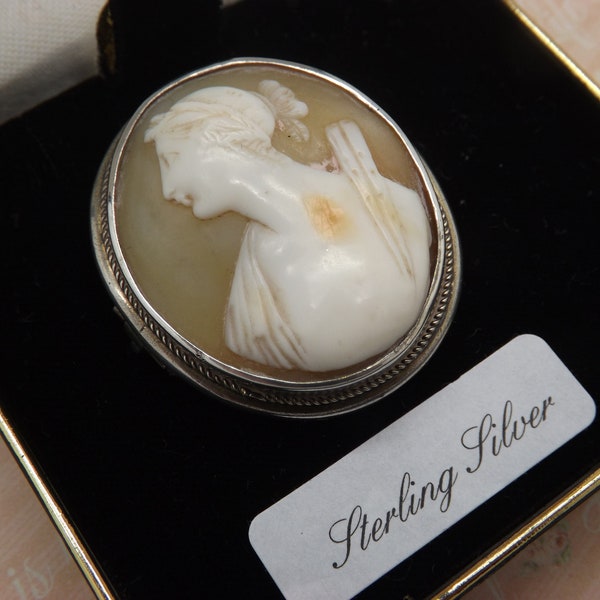 A beautiful Victorian hand carved cameo antique jewelry brooch made with a silver mount set with a shell cameo of a young maiden