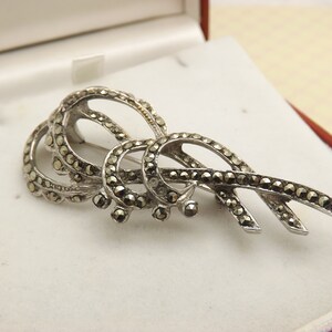 A lovely abstract leaf spray design vintage jewelry brooch made in fine polished openwork silvertone metal set with marcasite stones
