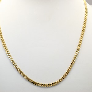 Un hermoso collar de bisutería con cadena en tono dorado elaborado con finos eslabones planos entrelazados.