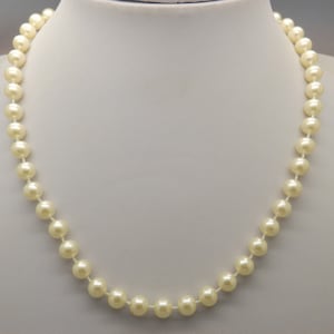 A fine single row of imitation pearls vintage jewelry necklace made with shiny pale cream coloured pearl beads with cord knotted inbetween
