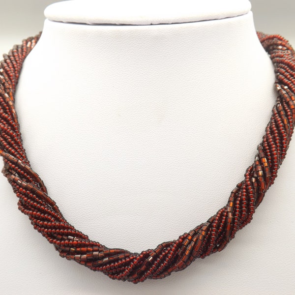 A fine Marks and Spencer multi strand costume jewelry necklace made up of woven rows of shiny polished mixed shape and size deep red beads