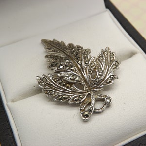 A lovely period stylized leaf design  vintage jewelry brooch made in openwork chrome/ silvertone metal set with sparkly marcasites stones.