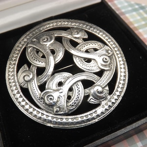 A super large round Celtic viking serpent design vintage jewelry brooch made in antiqued silvertone open work metal with engraved decoration