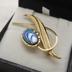 A beautiful abstract design leaf stem design vintage jewelry brooch made in goldtone metal inlaid with shiny polished abalone shell