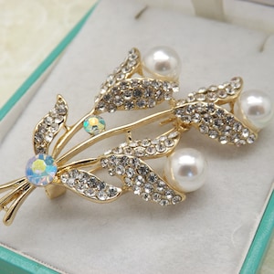 A lovely flower spray costume jewelry brooch made in goldtone metal with sparkly clear white diamante and rainbow stones plus faux pearls