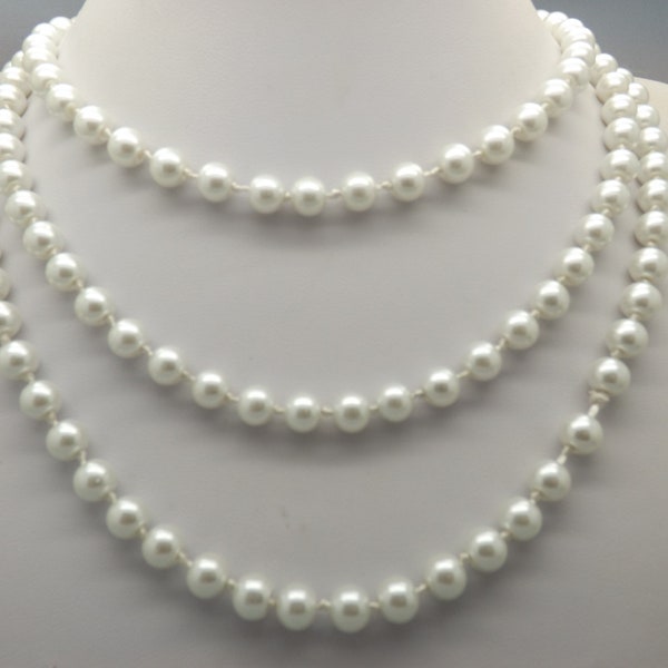 Un superbe collier long et simple de perles d'imitation, tissé à la main, composé de perles brillantes crème pâle nouées entre les deux.