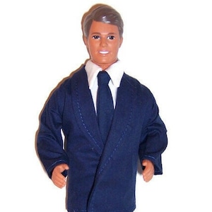 May include: A doll wearing a dark blue suit with a white shirt and a dark blue tie.