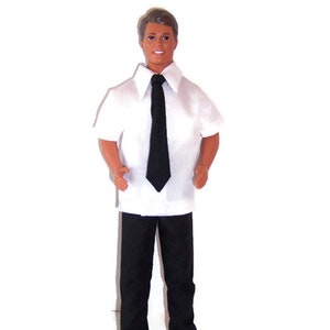 Pu&ograve; includere: Una bambola che indossa una camicia bianca a maniche corte con una cravatta nera e pantaloni neri.