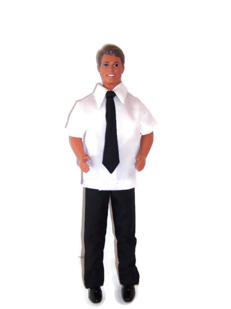 Pu&ograve; includere: Una bambola che indossa una camicia bianca a maniche corte con una cravatta nera e pantaloni neri.