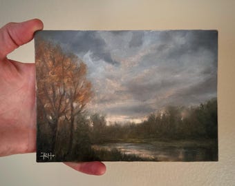 May include: A painting of a landscape with a river, trees, and a cloudy sky. The trees are in the foreground and the river is in the middle ground. The sky is a light blue with dark clouds.