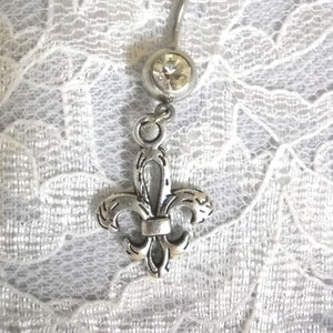 May include: Silver belly button ring with a clear crystal and a fleur-de-lis charm.