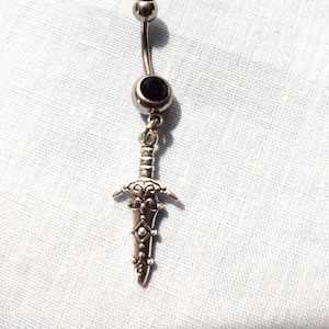 May include: A silver body piercing with a black gem and a sword charm.
