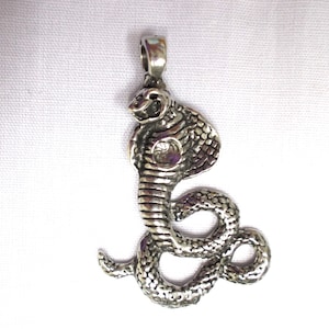 May include: Silver-toned pendant featuring a detailed cobra snake design. The snake is coiled with its head raised and its mouth open.