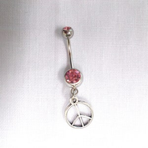 May include: A silver belly button ring with a pink gem and a peace sign charm.