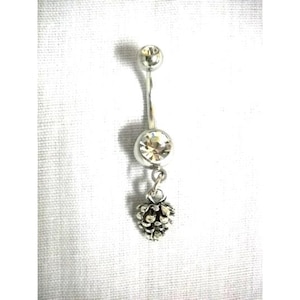 May include: A silver-toned belly button ring featuring a curved barbell with a small top ball, a larger clear round faceted crystal set in the center, and a dangling charm shaped like a textured pinecone at the bottom of the piece.