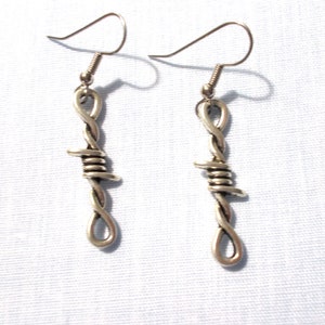 May include: A pair of silver earrings shaped like barbed wire. The earrings have a simple hook closure.