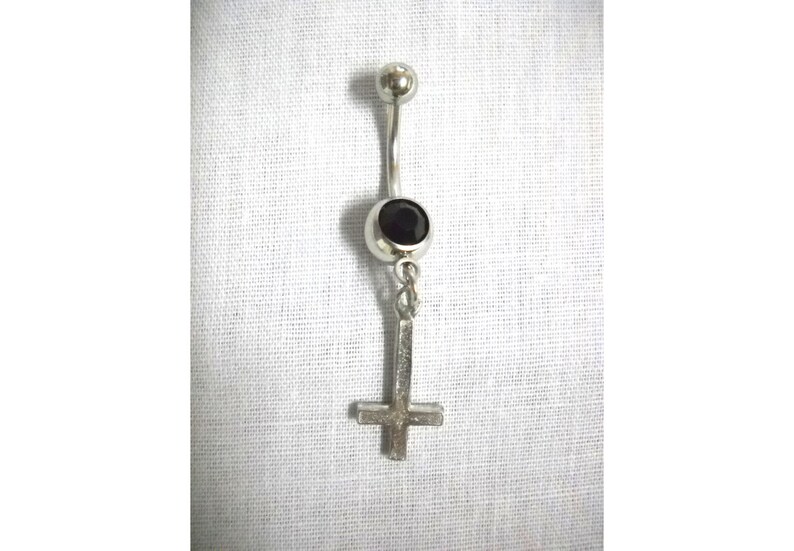 May include: Silver body piercing with a black gem and a silver upside down cross charm.