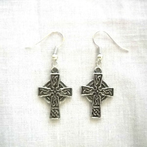 May include: A pair of silver Celtic cross earrings with intricate knotwork designs. The earrings have a simple hook closure.