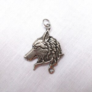 May include: Silver wolf head pendant charm with a detailed design. The pendant has a loop at the bottom for attaching to a necklace or bracelet.