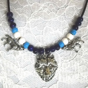 May include: A silver wolf pendant necklace with blue and white beads. The pendant is detailed and has a textured finish.