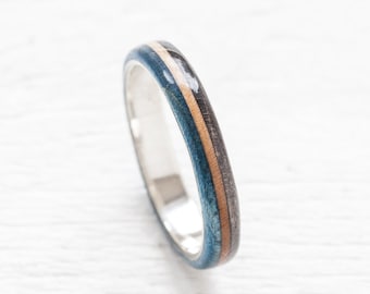 May include: A silver band ring with a blue, brown, and beige wood inlay.