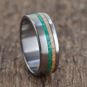 May include: A silver titanium ring with a green and brown wood inlay.