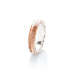 May include: A wooden ring with a silver band. The wood is a light brown colour with darker brown stripes.