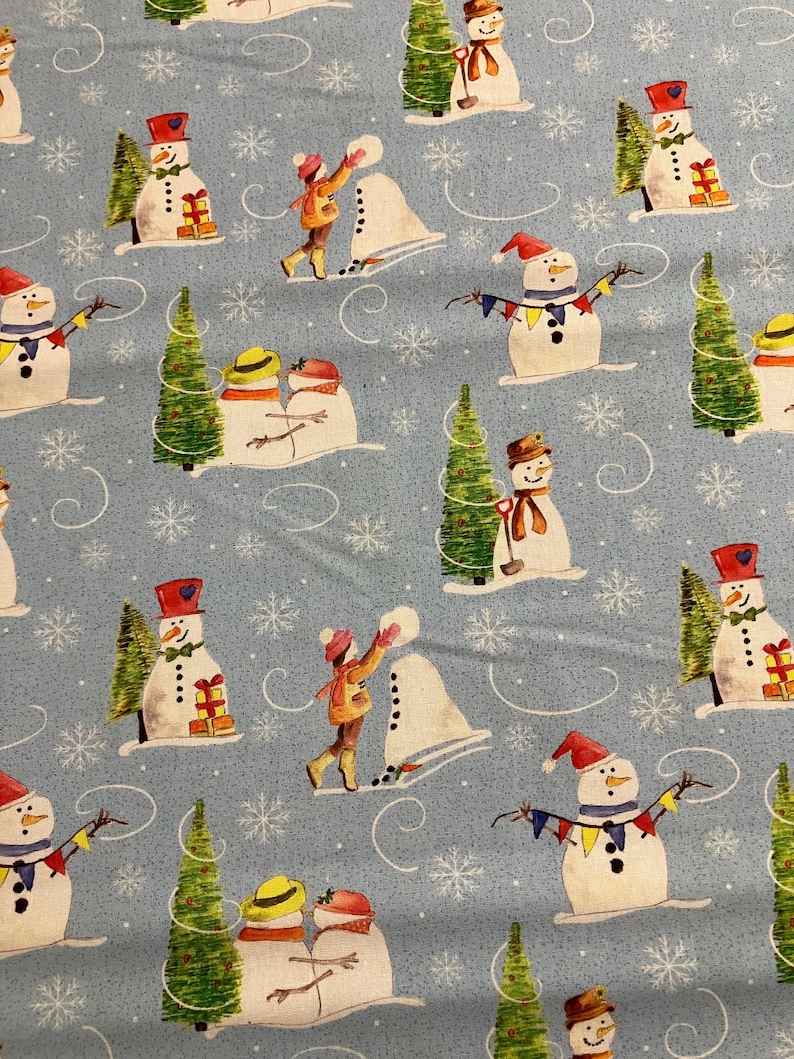 K&ouml;nnte beinhalten: Ein blauer Stoff mit einem sich wiederholenden Muster aus Schneem&auml;nnern, Weihnachtsb&auml;umen und Schneeflocken. Die Schneem&auml;nner tragen H&uuml;te und Schals, und einige halten Geschenke. Die B&auml;ume sind mit Kugeln und Lichtern geschm&uuml;ckt. Die Schneeflocken sind &uuml;ber den gesamten Stoff verteilt.