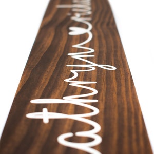 May include: A wooden sign with the words "Love my tribe" written in white cursive lettering. A small heart is included in the lettering.