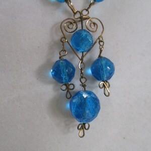 May include: A blue glass bead necklace with a heart-shaped wire design and dangling beads.
