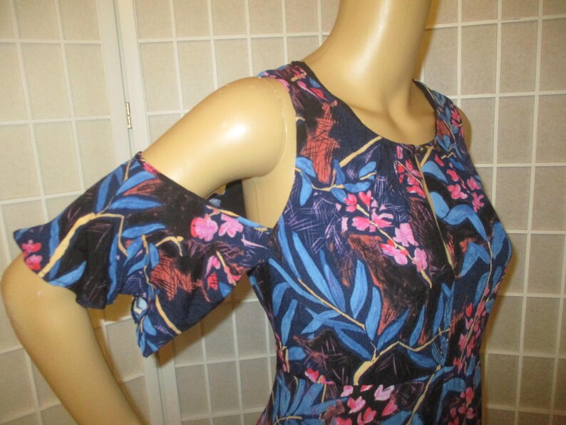 May include: A blue and black floral print cold shoulder dress with a ruffled sleeve. The dress has a scoop neck and a loose fit.