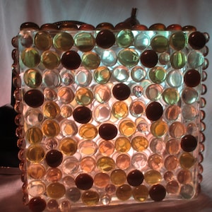 May include: A square glass lampshade with a mosaic of clear, brown, and green glass beads.
