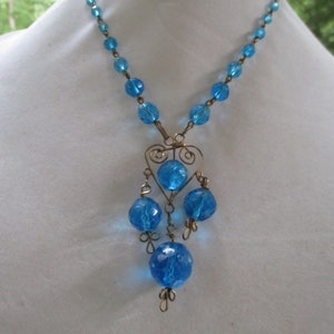 May include: A blue glass bead necklace with a wire heart pendant and dangling blue glass beads.