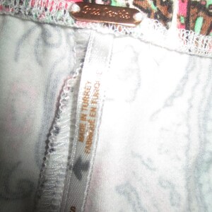 Puede incluir: Primer plano de una prenda con un colorido estampado de cachemira en rosa, verde y marr&oacute;n. Una peque&ntilde;a etiqueta met&aacute;lica rectangular que dice "Free People". Una etiqueta que dice "MADE IN TURKEY FABRIQUE EN TURQUIE" y la talla es "S".