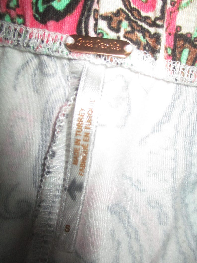 Puede incluir: Primer plano de una prenda con un colorido estampado de cachemira en rosa, verde y marr&oacute;n. Una peque&ntilde;a etiqueta met&aacute;lica rectangular que dice "Free People". Una etiqueta que dice "MADE IN TURKEY FABRIQUE EN TURQUIE" y la talla es "S".
