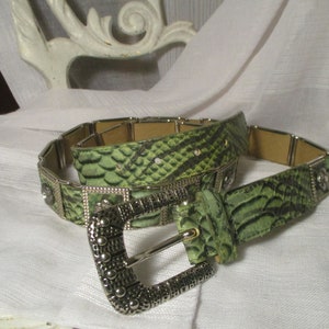 May include: A green snakeskin belt with a silver buckle. The buckle is decorated with small silver studs.