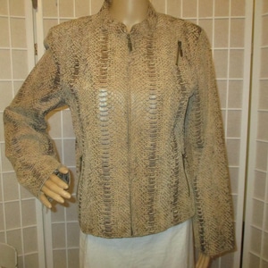 May include: A beige and brown jacket featuring a textured snakeskin pattern throughout. The garment includes a full-length front zip closure, a stand-up collar, long sleeves, and two zipped pockets located on the lower front section.