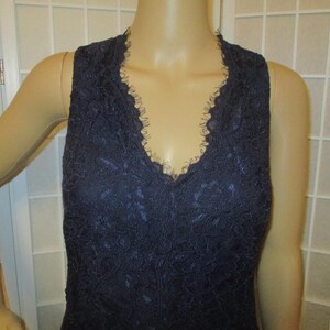May include: A sleeveless navy blue lace top with a V-neckline.