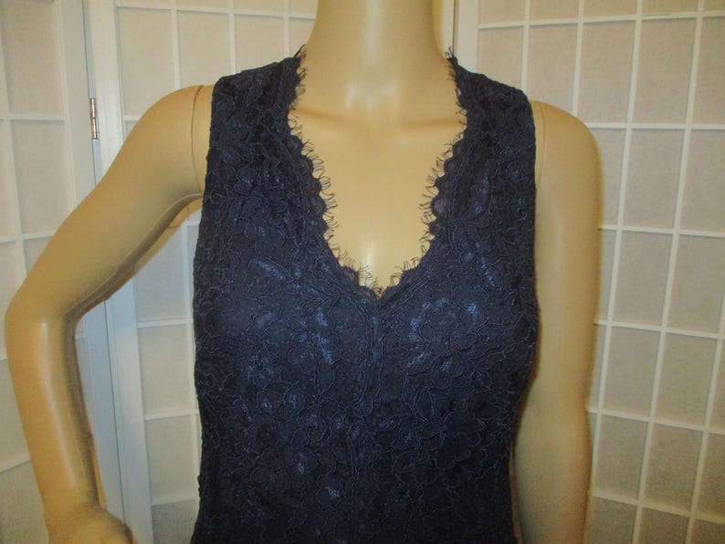 May include: A sleeveless navy blue lace top with a V-neckline.