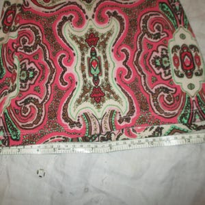 Puede incluir: Primer plano de una tela con un estampado de cachemira en tonos rosa, marr&oacute;n, verde y crema. Una cinta m&eacute;trica se coloca a lo largo del borde inferior de la tela, mostrando medidas en cent&iacute;metros.