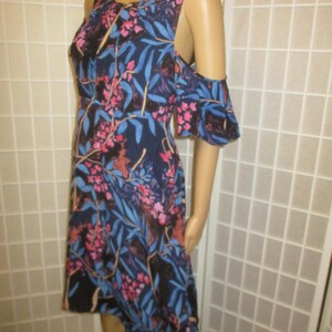 May include: A blue and pink floral print dress with cold shoulder straps and a high-low hemline.