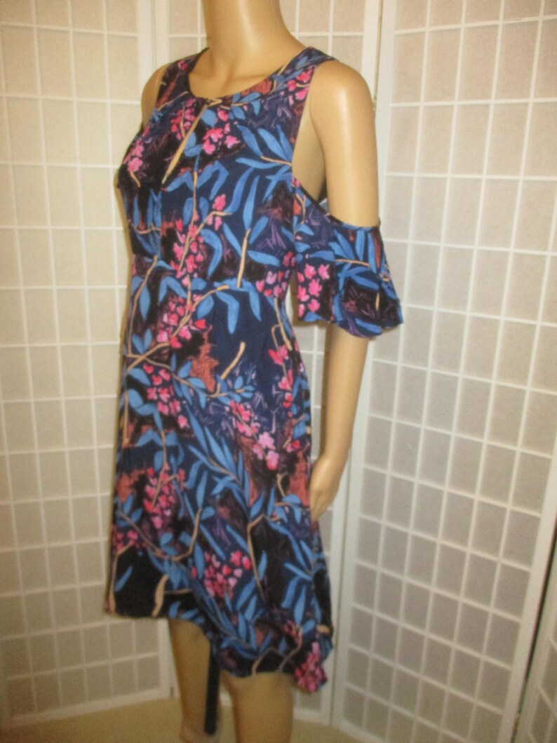 May include: A blue and pink floral print dress with cold shoulder straps and a high-low hemline.