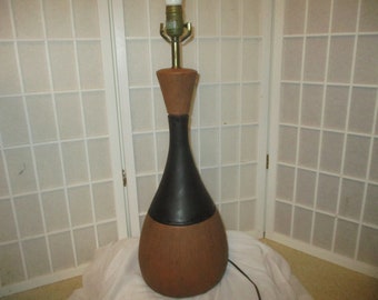 May include: A mid-century modern table lamp with a brown and black ceramic base. The lamp has a simple design with a rounded shape and a black cord.