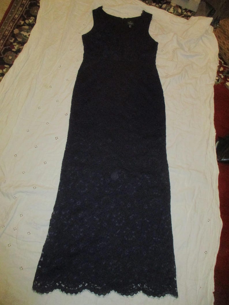 May include: A long, sleeveless, black lace dress with a scalloped hem.