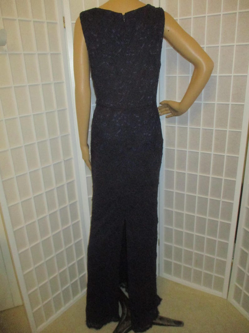 May include: A long, sleeveless, dark purple lace dress with a scoop neck and a slit in the back.