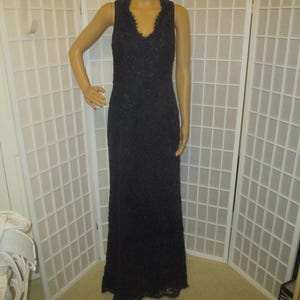 May include: A long, navy blue lace dress with a V-neckline. The dress is sleeveless and has a fitted bodice and a flowing skirt.