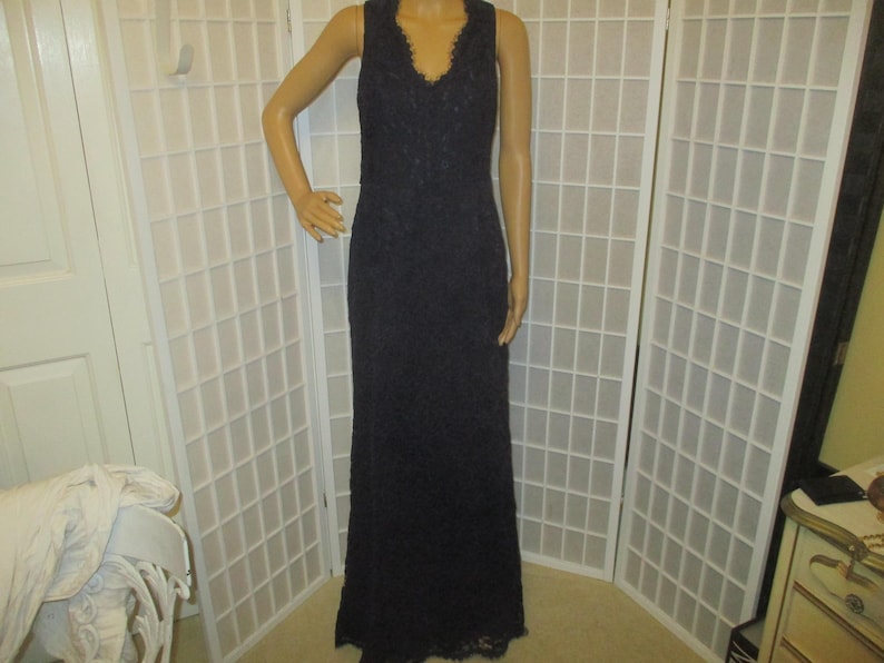 May include: A long, navy blue lace dress with a V-neckline. The dress is sleeveless and has a fitted bodice and a flowing skirt.